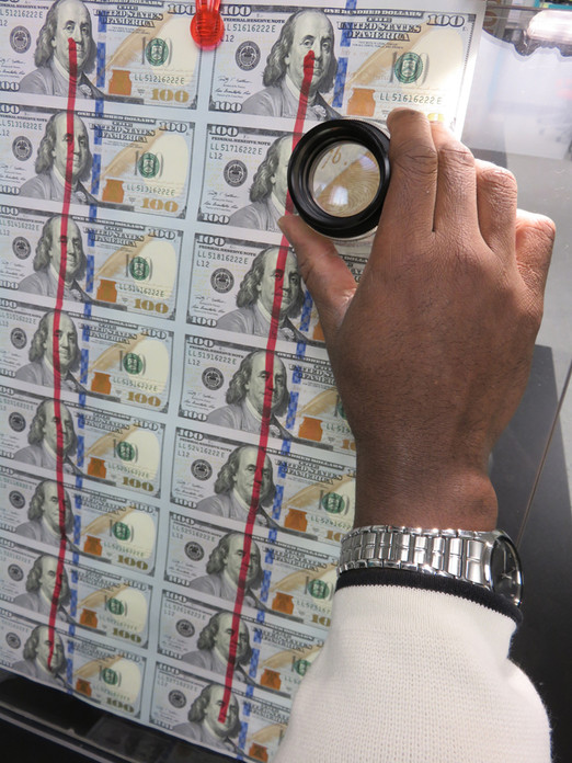 A sheet of $100 notes is inspected for overall quality.