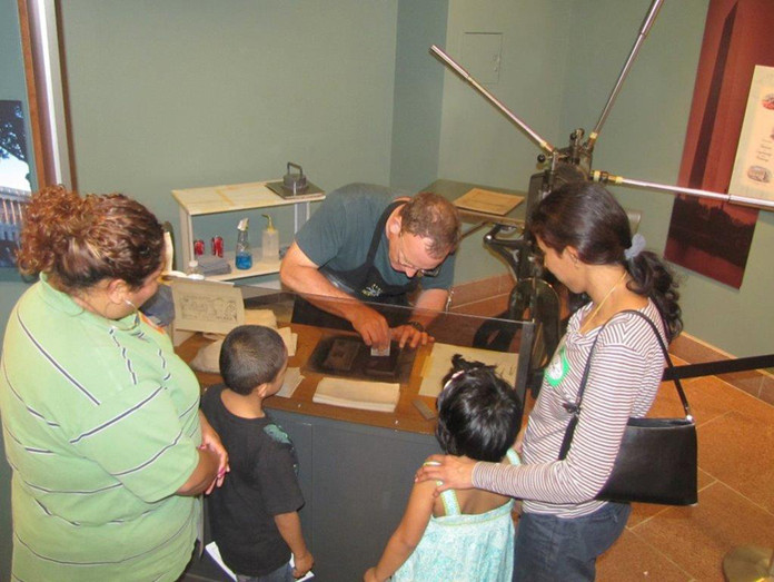 A plate printer applies ink to an engraved plate before it is pulled from the Spider Press.