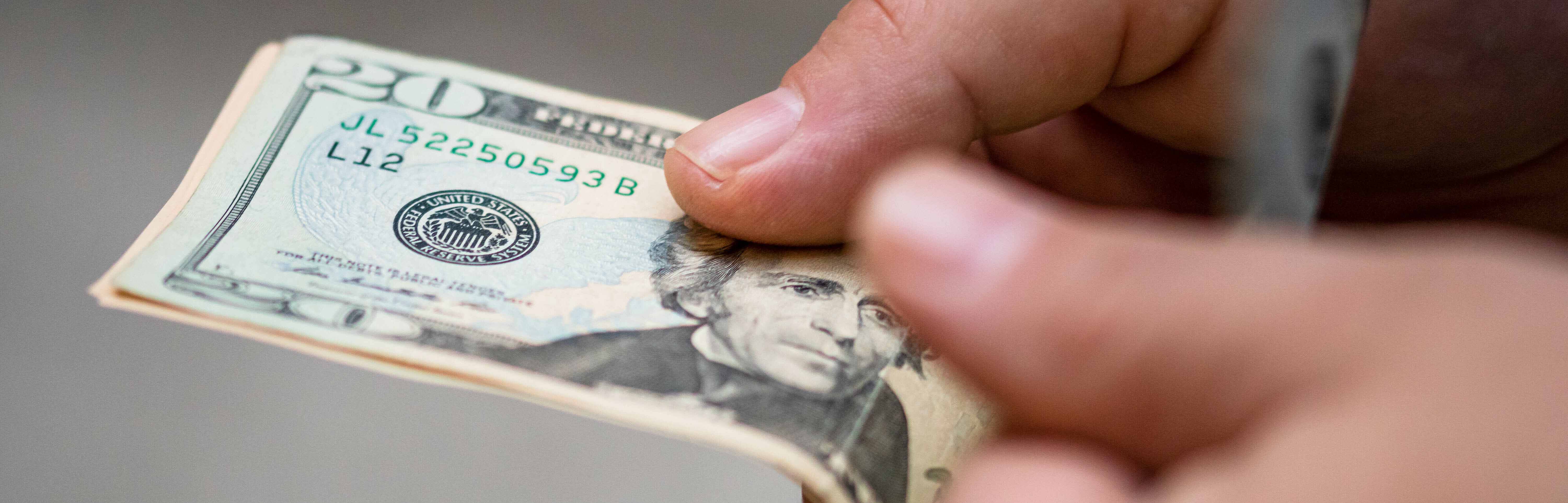 Two hands holding a $20.