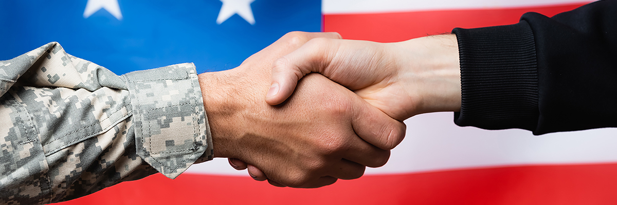 Two hands shaking in front of the American flag.