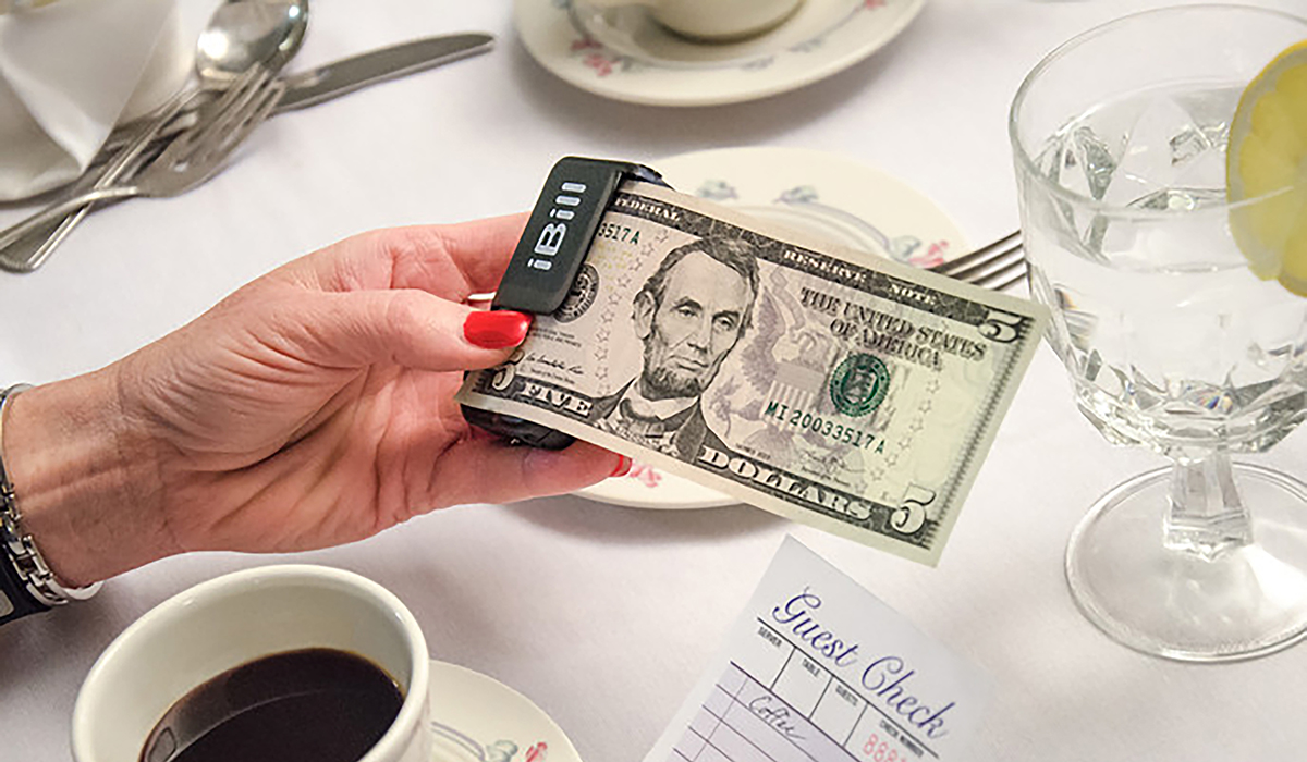 iBill currency reader reading $5 bill at restaurant table